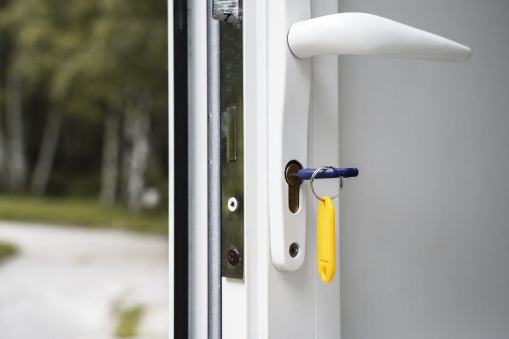 Ajar white door with white handles and a key in the lock